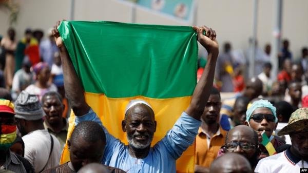 FILE - A supporter of the junta in Mali holds up the natio<em></em>nal flag during a rally in Bamako on May 13, 2022. Families of opposition politicians who were arrested by the junta said on June 26, 2024, that they have been moved to prisons.
